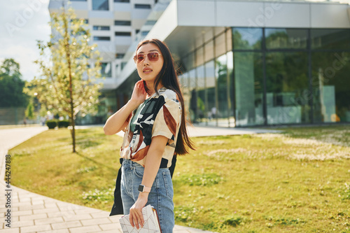 In sunglasses. Young asian woman is outdoors at daytime