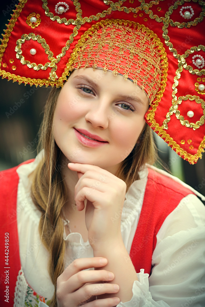 Portrait of a beautiful girl in a national Russian costume with a kokoshnik on her head.A Russian girl in a traditional red sundress, white shirt and crown.Blonde with a long braid.Folk, retro, ethno. Portrait of a beautiful girl in a national Russian costume with a kokoshnik on her head.A Russian girl in a traditional red sundress, white shirt and crown.Blonde with a long braid.Folk, retro, ethno.