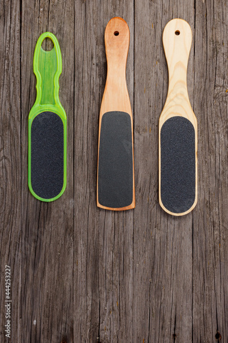 Wooden pedicure graters and a plastic foot file on wooden boards.
