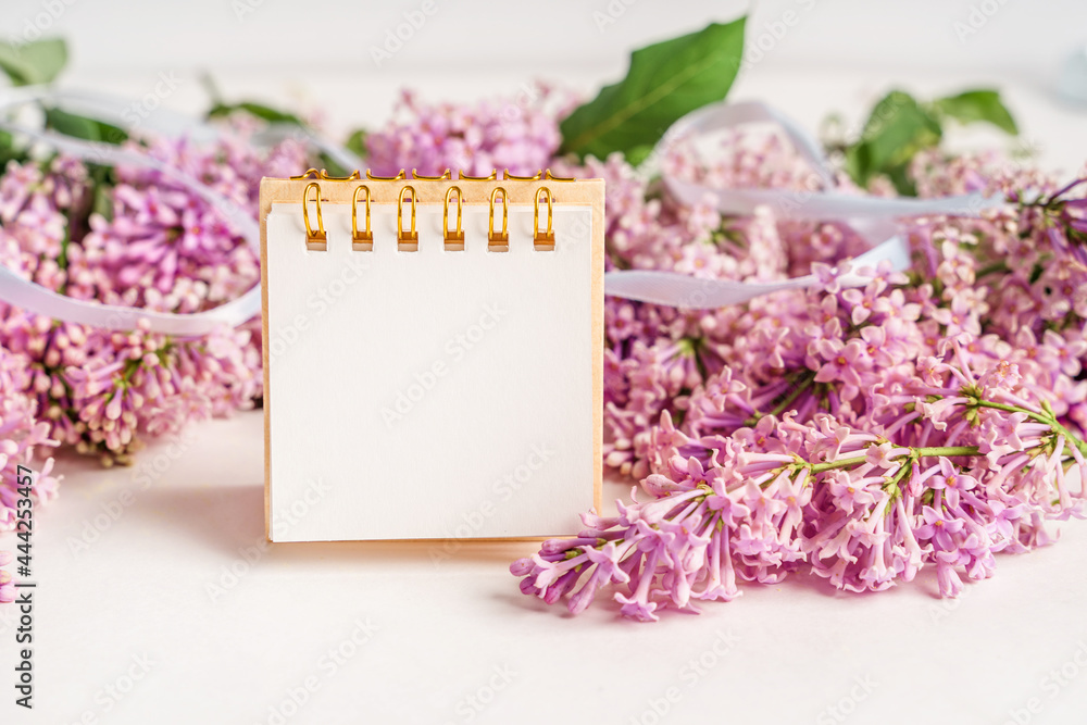 A beautiful floral composition and an empty paper notepad for text. Floral spring background with lilac. Copy space A beautiful floral composition and an empty paper notepad for text. Floral spring background with lilac. Copy space