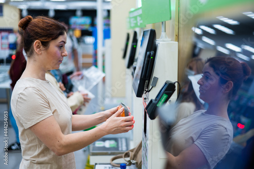 Obraz na plátně Caucasian woman uses a self-checkout counter