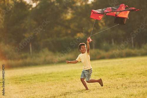 Running with red kite. African american kid have fun in the field at summer daytime #444254295