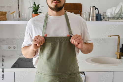 Photo A man in a kitchen apron stands in a modern kitchen