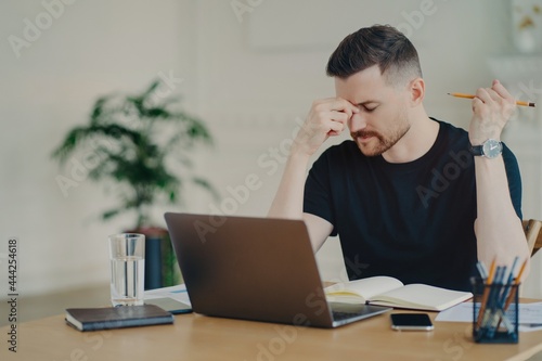 Frustrated business person feeling tired while working at his workplace at home or office photo