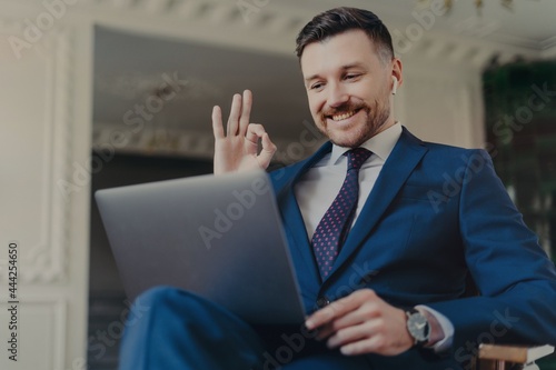 Cheerful businessman boss gesturing while communicating through video conference