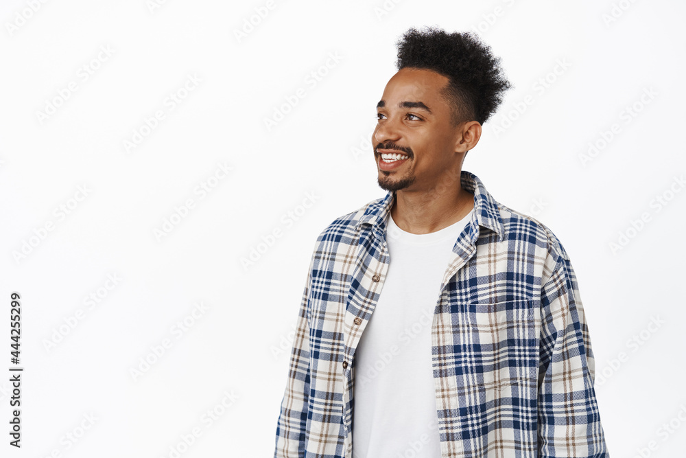 Portrait of modern hipster guy with afro hairstyle and moustache, looking aside at sale banner, staring left and smiling happy, glancing at smth interesting, promo text on empty space Portrait of modern hipster guy with afro hairstyle and moustache, looking aside at sale banner, staring left and smiling happy, glancing at smth interesting, promo text on empty space