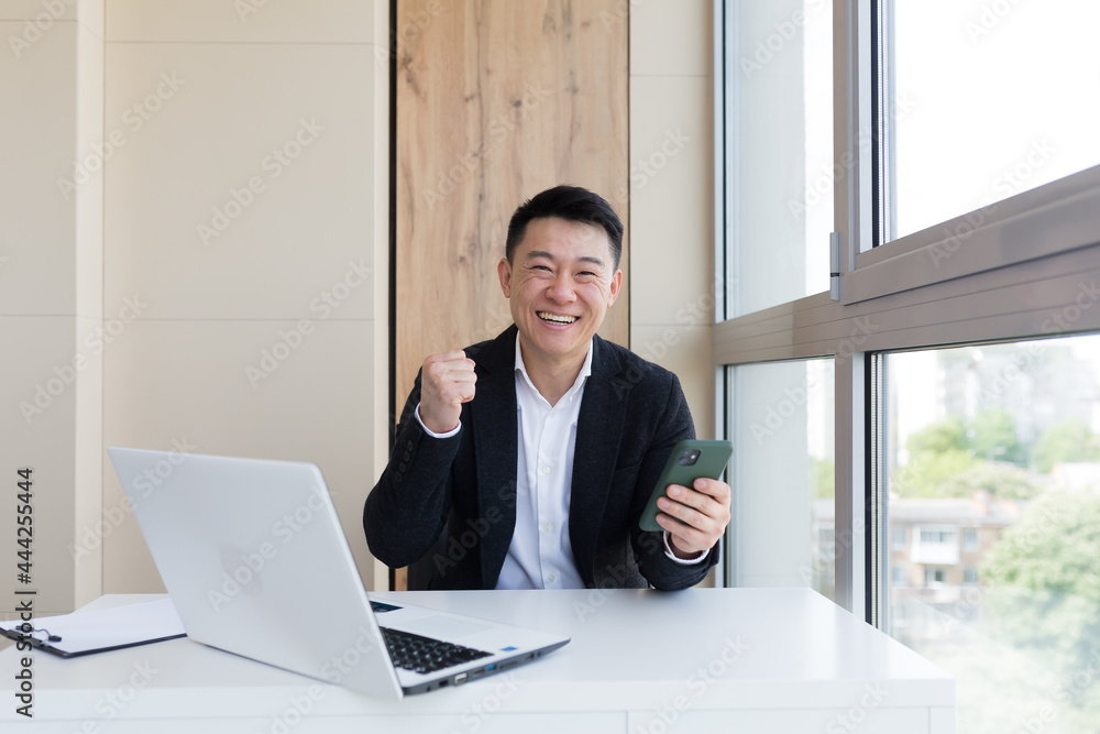 Happy young Asian business man in office, looking at camera, with emotions of winner or victory, financial promotion sports betting. The man exclaims happily while playing the game. Excited with joy, Happy young Asian business man in office, looking at camera, with emotions of winner or victory, financial promotion sports betting. The man exclaims happily while playing the game. Excited with joy,
