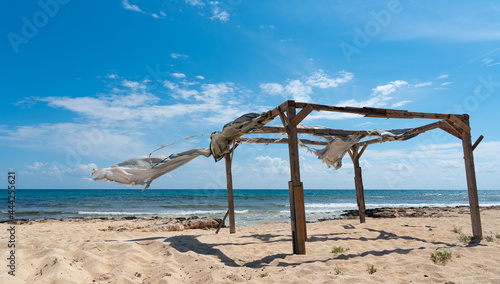 Wooden abandoned holiday pergola on a windy day at the beach. © Michalis Palis