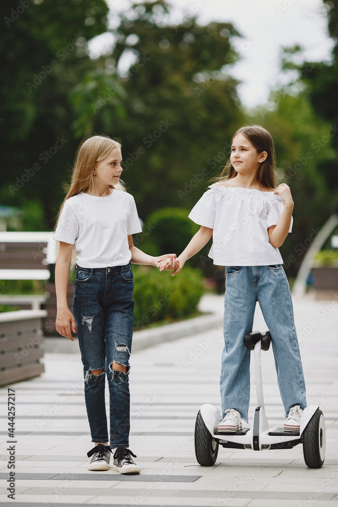 Children learn to ride hoverboard in a park on sunny summer day Children learn to ride hoverboard in a park on sunny summer day