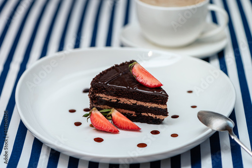 Chocolate Cake Served In Portion  On A Striped Tablecloth. White Cup Of Cappuccino.  Sea Style Concept. Blue And White Vertical Stripes. Side  View. Selective Focus.