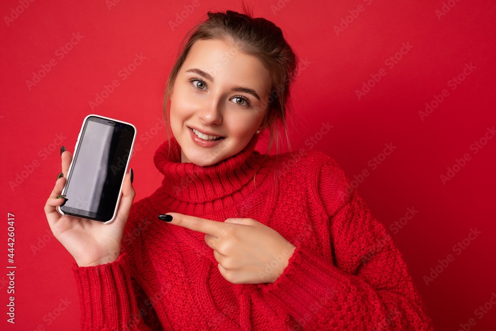Photo of beautiful smiling young woman good looking wearing casual stylish outfit standing isolated on background with copy space holding smartphone showing phone in hand with empty screen display for Photo of beautiful smiling young woman good looking wearing casual stylish outfit standing isolated on background with copy space holding smartphone showing phone in hand with empty screen display for