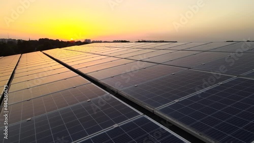Blue photovoltaic solar panels mounted on building roof for producing clean ecological electricity at sunset. Production of renewable energy concept. photo