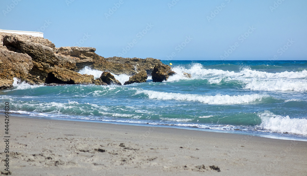 Waves crashing against a breakwater on the beach during a day with the Mediterranean sea rough with strong waves