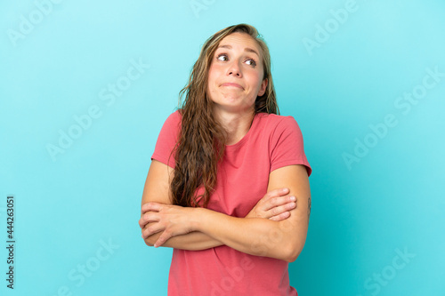 Young caucasian woman isolated on blue background making doubts gesture while lifting the shoulders