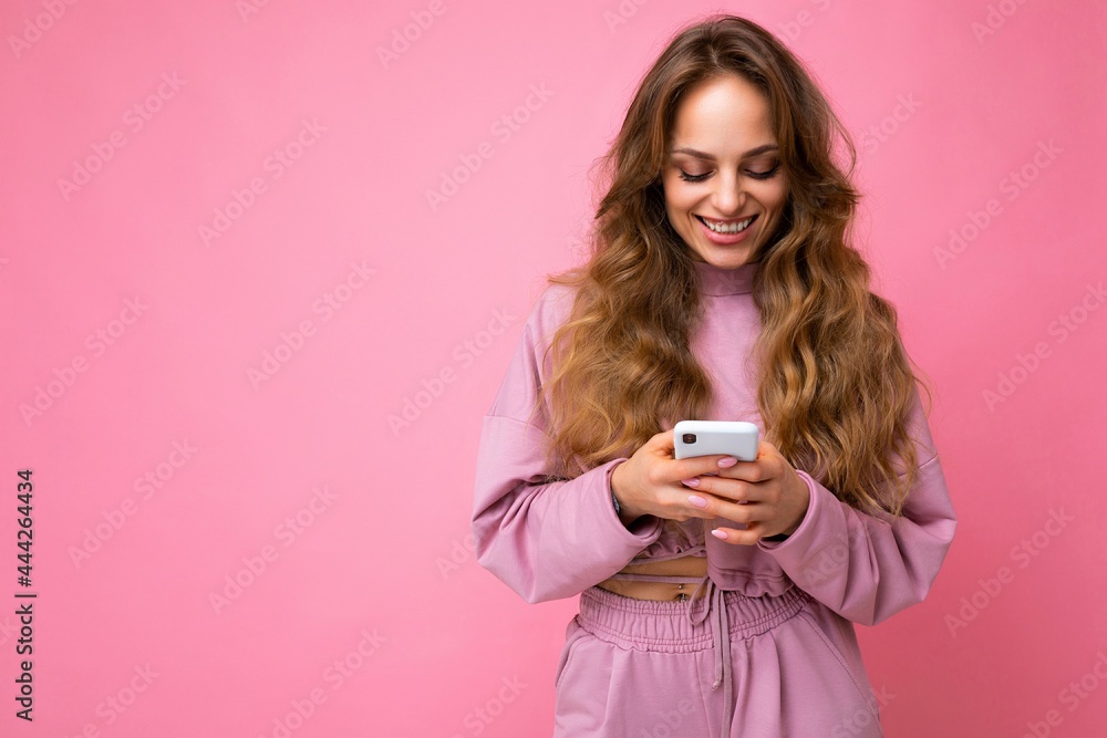 Beautiful smiling young woman wearing casual clothes standing isolated over background surfing on the internet via phone looking at mobile screen Beautiful smiling young woman wearing casual clothes standing isolated over background surfing on the internet via phone looking at mobile screen