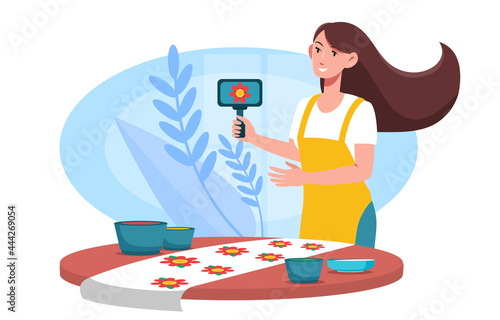 Smiling female character is printing floral pattern on fabric using woodblocks and paint