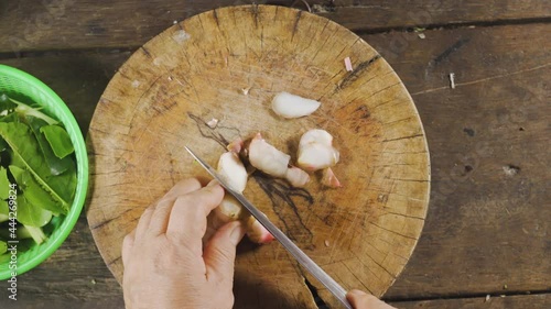 Old asian slicing galangal with knife on her hands. Preparing for making food menu. Thai food. Top View.