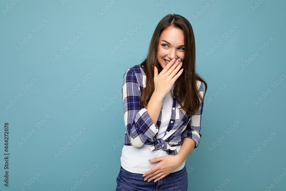 Young positive happy jyful amusing funny laughing attractive pretty brunet woman with sincere emotions wearing stylish check shirt standing isolated on blue background with empty space Young positive happy jyful amusing funny laughing attractive pretty brunet woman with sincere emotions wearing stylish check shirt standing isolated on blue background with empty space