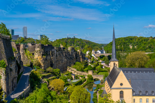 Vertical view of Luxembourg-City with Neumünster abbey, medieval houses in the lower city, trees, and Kirchberg skyline in the background