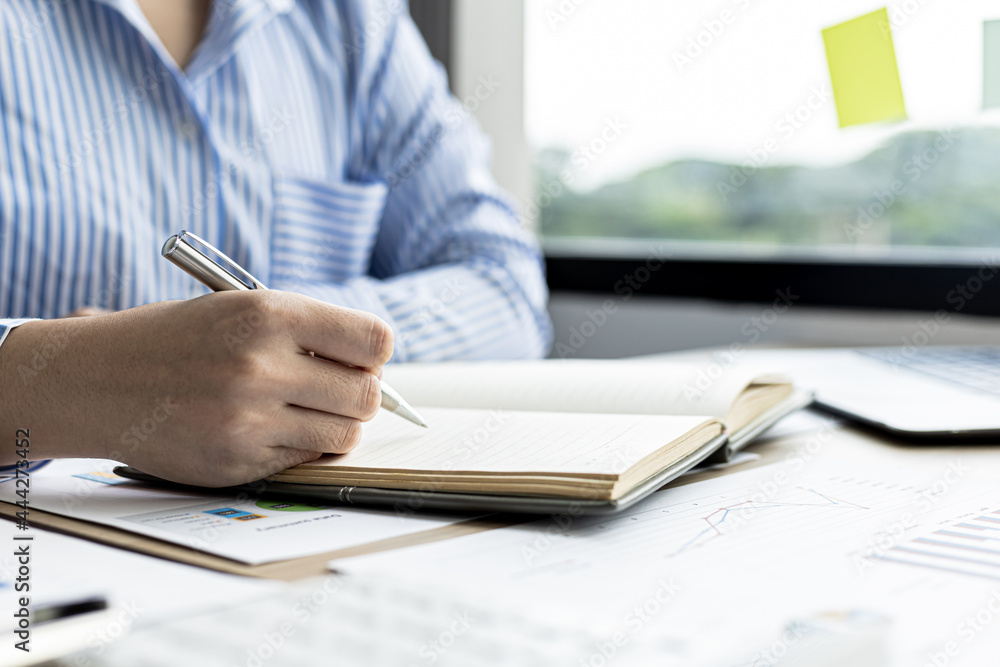 A woman is taking notes in a notebook, she works from home due to the epidemic, she records details of tasks assigned by her supervisor through a video conference. The idea of working from home. A woman is taking notes in a notebook, she works from home due to the epidemic, she records details of tasks assigned by her supervisor through a video conference. The idea of working from home.