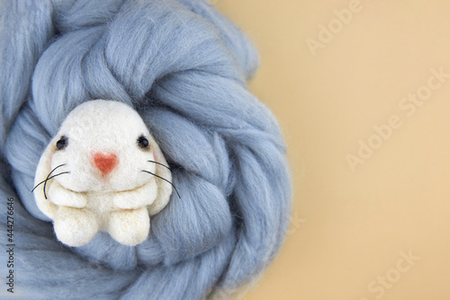 Handmade bunny felted of wool on a beige background.