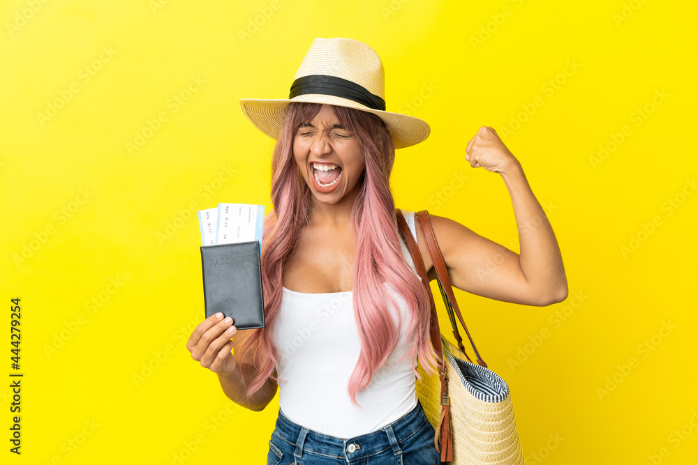 Young mixed race woman holding passport and beach bag isolated on yellow background doing strong gesture Young mixed race woman holding passport and beach bag isolated on yellow background doing strong gesture