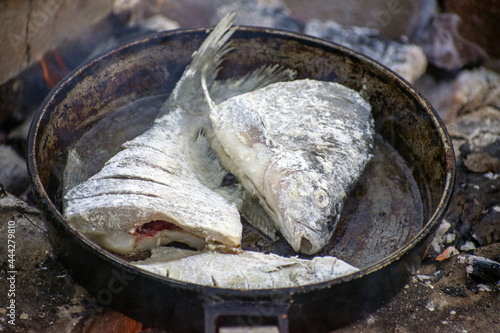 fried fish in a pan over an open fire