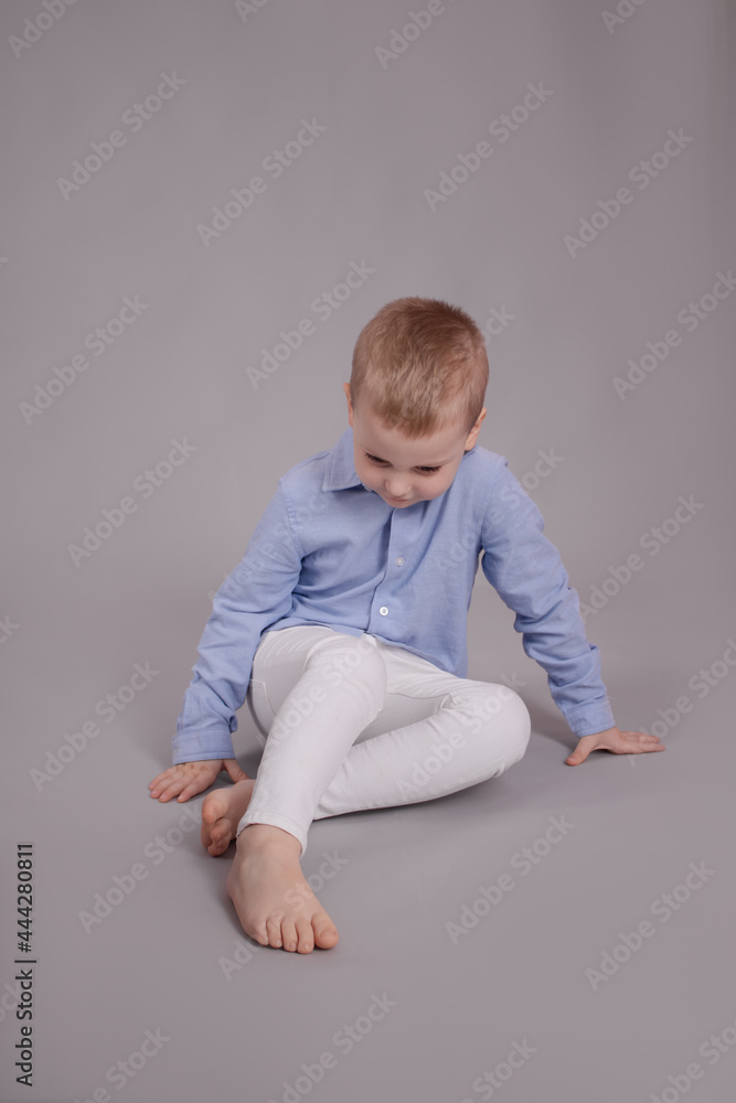 charming little preschool boy in white pants and blue shirt on gray background. child, kid charming little preschool boy in white pants and blue shirt on gray background. child, kid
