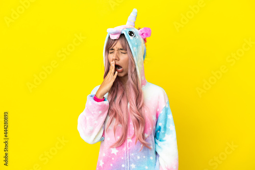 Young mixed race woman wearing a unicorn pajama isolated on white background yawning and covering wide open mouth with hand