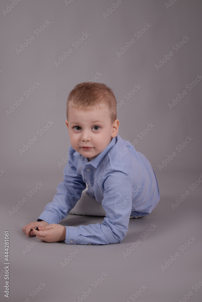 charming little preschool boy in white pants and blue shirt on gray background. child, kid charming little preschool boy in white pants and blue shirt on gray background. child, kid