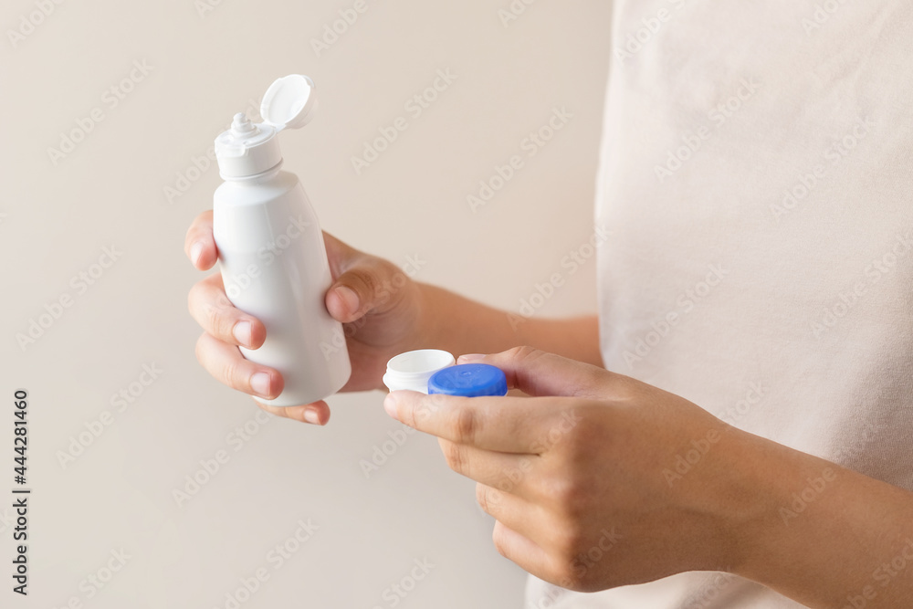 Women's hands with a solution and a container for contact lenses. Close-up Women's hands with a solution and a container for contact lenses. Close-up