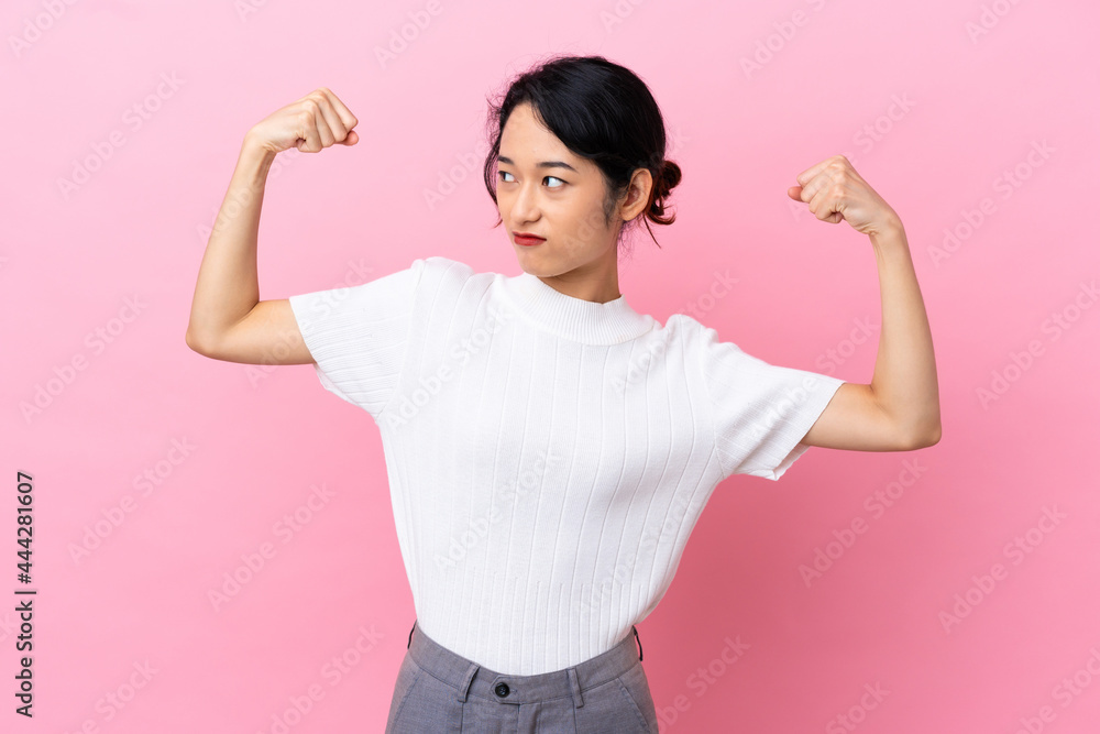Young Vietnamese woman isolated on pink background doing strong gesture Young Vietnamese woman isolated on pink background doing strong gesture