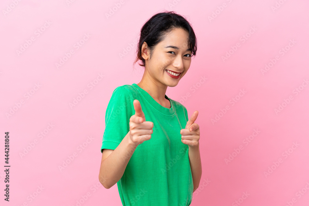 Young Vietnamese woman isolated on pink background pointing to the front and smiling Young Vietnamese woman isolated on pink background pointing to the front and smiling