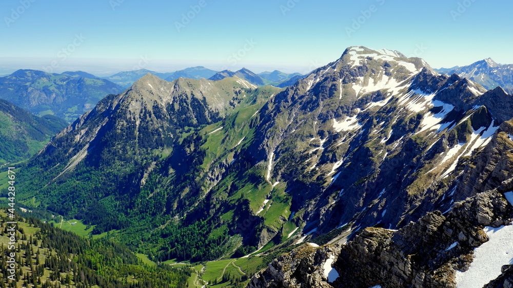 Blick vom Gipfel des Nebelhorns zum Hindelanger Klettersteig mit grüner Landschaft im Frühling