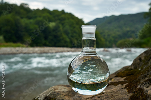 Bottle of drinking water on the shore of a mountain river.