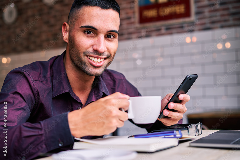 Cheerful Hispanic businessman using smartphone during break Cheerful Hispanic businessman using smartphone during break