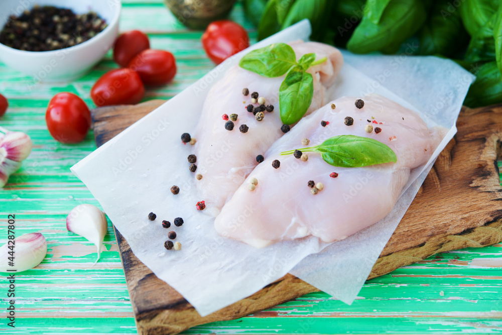 Raw chicken breast marinated for baking on a wooden board Raw chicken breast marinated for baking on a wooden board