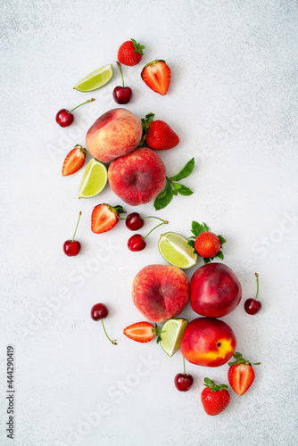 Peach, cherry, strawberry, lime, mint and nectarine on grey textured background. Fresh juicy fruits and berries. Healthy paleo diet food. Superfood nutrition concept. Summer snack. Top view, flat lay.