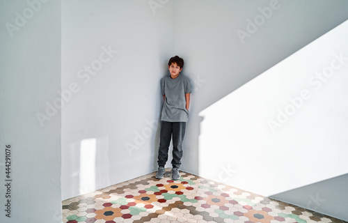 Lonely sad kid standing in corner photo