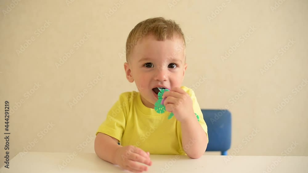 toddler boy plays draws on a piece of paper with a red pen sitting at a white table. educational game Montessori fine motor skills. early development concept toddler boy plays draws on a piece of paper with a red pen sitting at a white table. educational game Montessori fine motor skills. early development concept