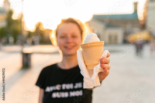 A young woman is holding  eating and enjoying an ice-cream cone