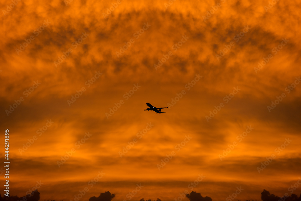 Commercial airplane flying through clouds in dramatic sunset light. Travel concept