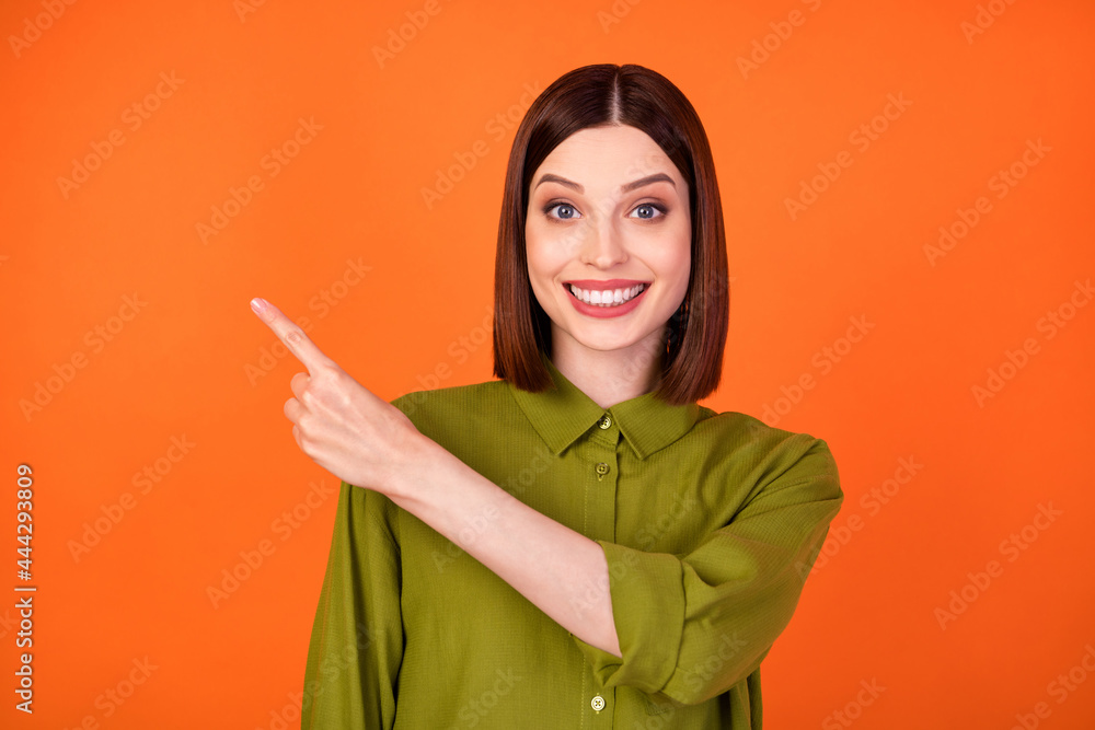 Photo of funny short hairdo young lady point empty space wear khaki shirt isolated on orange color background Photo of funny short hairdo young lady point empty space wear khaki shirt isolated on orange color background