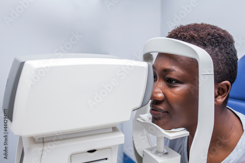 Black woman in optometry cabinet using a retinograph