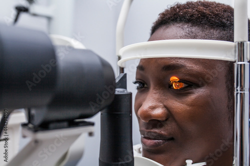 Black woman in optometry cabinet using a retinograph photo