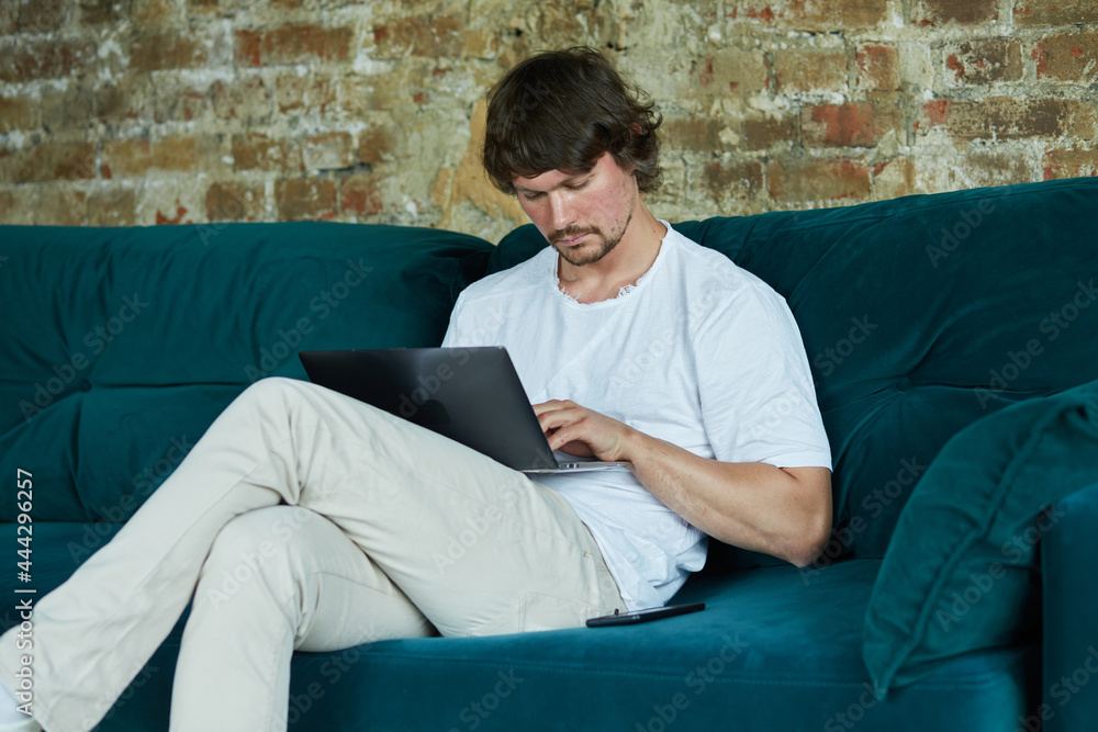 Concentrated serious young man working from home and enjoying distant job. male student using laptop for internet learning and creative writing and dreaming. Concentrated serious young man working from home and enjoying distant job. male student using laptop for internet learning and creative writing and dreaming.