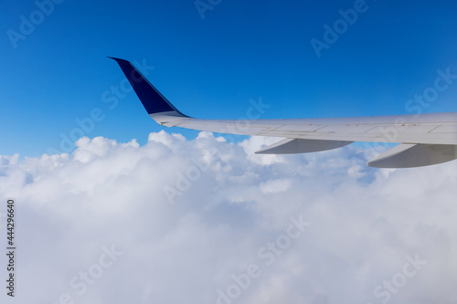 Wing of an airplane flying above the clouds of an aircraft