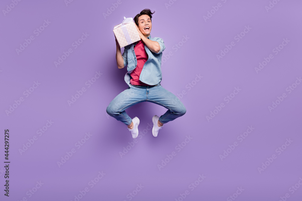 Full body photo of young guy excited shake present box curious receive jumper isolated over purple color background Full body photo of young guy excited shake present box curious receive jumper isolated over purple color background