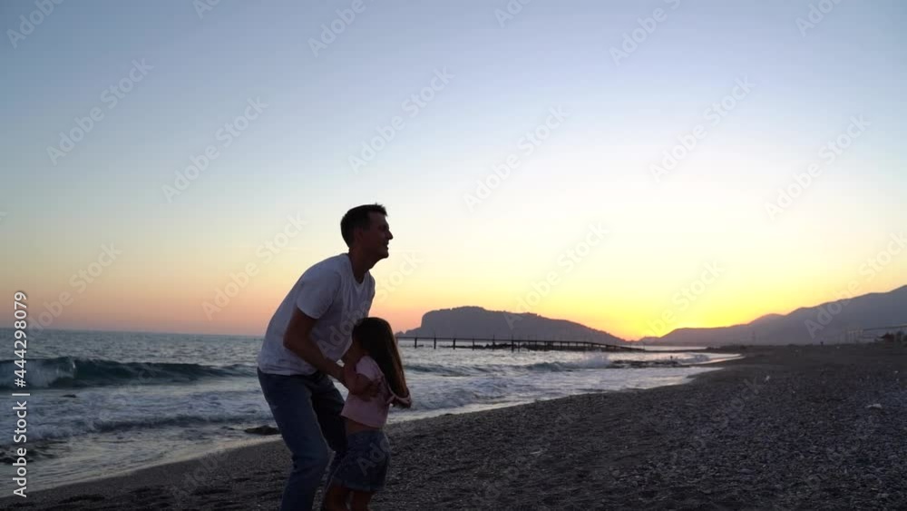 Father plays with daughter on beach at sunset time. Happy family concept. Slow motion. Father plays with daughter on beach at sunset time. Happy family concept. Slow motion.