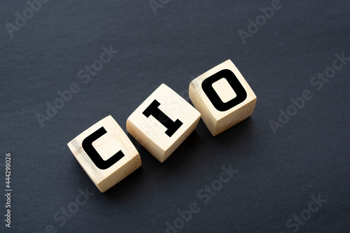 CIO written on wooden cubes - arranged in a vertical pyramid, grey and black background, CIO - short for Chief Information Investment Officer, business concept photo
